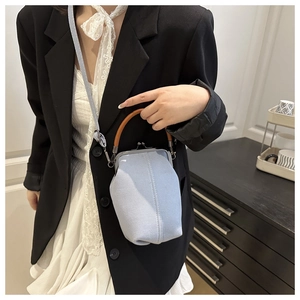 Modèle portant un sac docteur en denim bleu clair avec poignée brune et fermoir métal