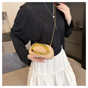 Beige strukturierte Mini-Tasche mit goldenem Metallgriff und Kettenriemen am Modell