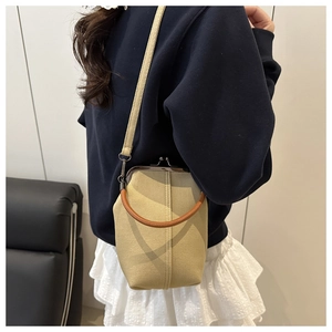 Détail du sac coquille en denim kaki avec poignée en cuir marron et fermoir métallique