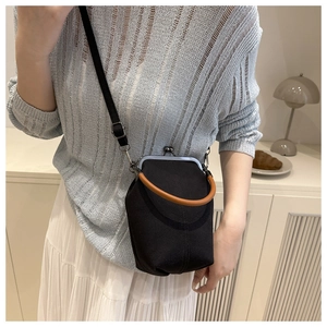 Détail d'un sac en toile vintage noir avec poignée ronde marron et fermoir métallique