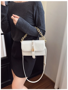 Detail of white leather shoulder bag with gold clasp and elegant metal chain strap