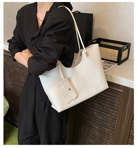 Close-up of white crocodile pattern tote bag with matching pouch shown on a model