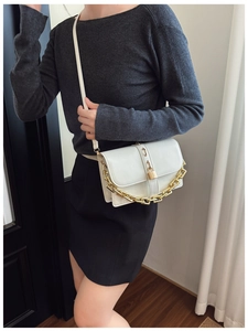 Close-up of a white glossy PU crossbody bag with bold gold chain and lock detail