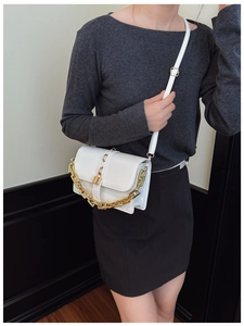 Detail of white crossbody bag with decorative gold chain and adjustable leather shoulder strap
