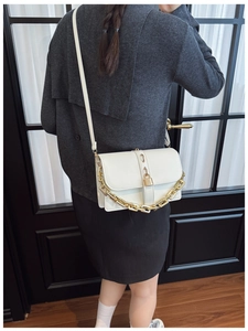 White faux leather crossbody bag with gold chain strap shown on a female model