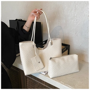 Detailed macro view of off-white tote bag set featuring woven leather texture and pouches