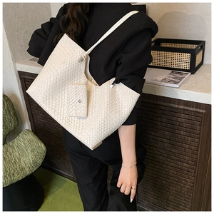 Detail of cream woven tote bag featuring checkered texture and matching zippered pouch
