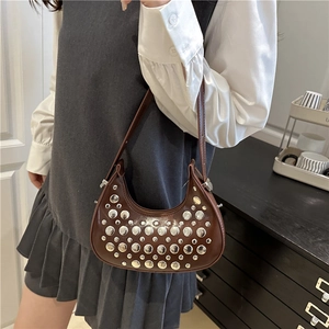 Brown leather crescent shoulder bag with silver rivets shown on a female model