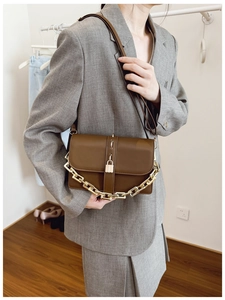 Detail of vintage dark brown crossbody bag with chunky gold chain strap and metal lock