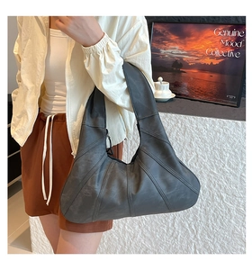 Detail der dunkelgrauen Hobo-Tasche mit gebogenem Nahtdesign und breitem Schultergurt