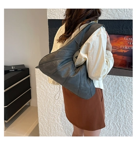 Detail of dark grey matte leather shoulder bag with decorative stitching on half-moon shape
