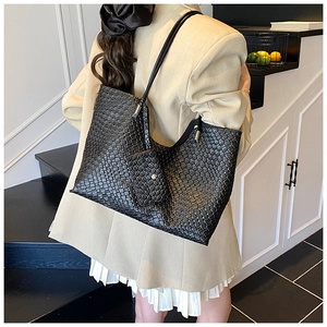 Black woven leather tote bag with small purse shown on model in a minimalist setting