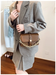 Detail of vintage brown leather crossbody bag with gold buckle and chain strap