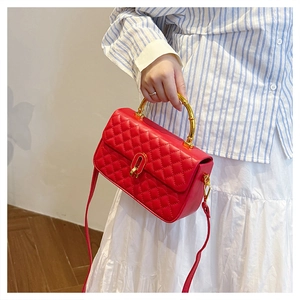 Detail showing red quilted handbag with bamboo-style gold metal handle and U-shaped lock