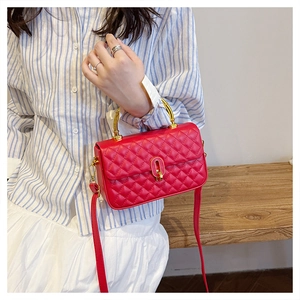 Detail of red quilted square bag featuring a distinctive golden bamboo style handle