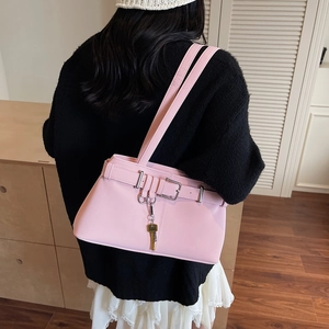 Pink faux leather underarm bag with decorative belt buckle and key pendant on a model