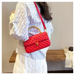 Detail of red quilted handbag with golden bamboo handle and metallic twist lock clasp