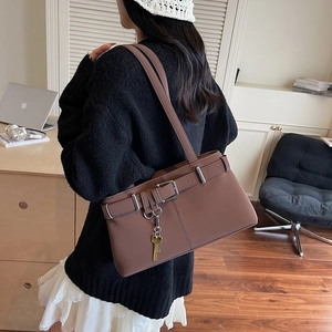 Brown vintage leather shoulder bag with buckle strap and gold key charm on model