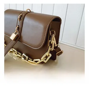Detail view of brown matte leather shoulder bag with gold chain and padlock accessory