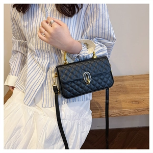 Detail of black quilted leather box bag with gold metal handle and twist lock