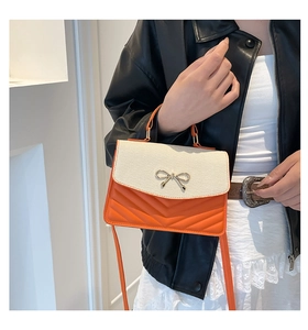 Détail du sac bandoulière en cuir matelassé orange avec nœud doré décoratif