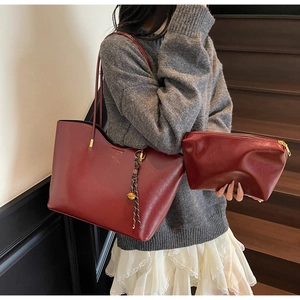 Detail of burgundy PU leather tote bag set featuring gold metal tassel and matching pouch