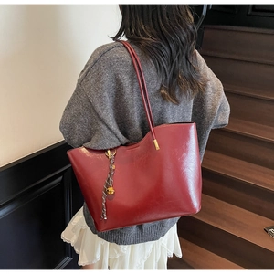 Detail of red vintage tote bag with metal ball pendant shown on model in soft lighting