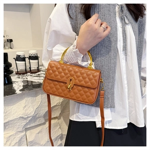 Detail of brown quilted crossbody bag with golden bamboo handle and turn-lock closure