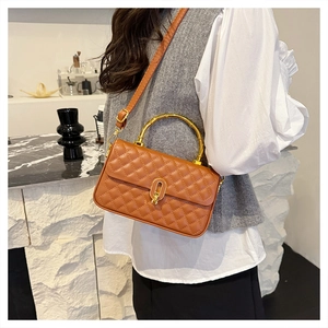 Detail of brown quilted bag with gold bamboo handle and ring lock worn by a model