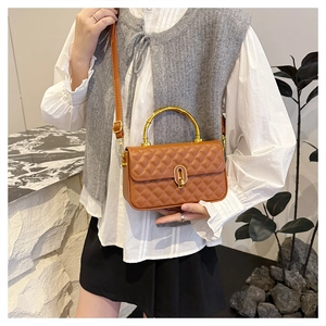 Detail of quilted brown crossbody bag featuring a golden bamboo handle and turn-lock