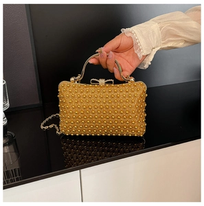 Detail of gold evening clutch with sequins, rhinestone bow clasp and metal handle