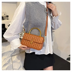 Detail of brown quilted bag showing bamboo handle and golden metal clasp hardware