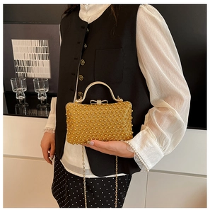 Detail of gold pearl evening bag with ornate bow buckle and chic metallic handle