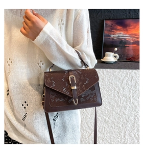 Detail of dark brown faux leather shoulder bag with snake skin pattern and gold buckle