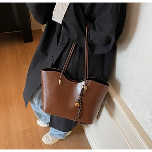 Classic brown large tote bag with woven strap detail worn by model in minimalist room