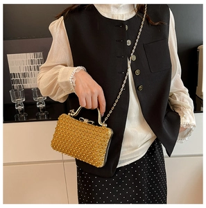 Detail of gold sequin evening bag featuring bow clasp and elegant chain strap