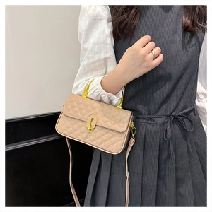 Close-up of beige quilted crossbody box bag with gold U-lock and metal arched handle