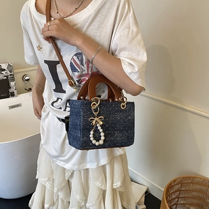 Blue denim crossbody bag with white polka dots and a golden pearl bow pendant charm