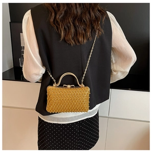 Detail of elegant gold beaded evening bag with metal bow clasp and chain strap