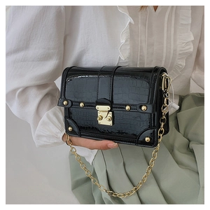 Detail of black crocodile-embossed box bag featuring gold rivets and square lock