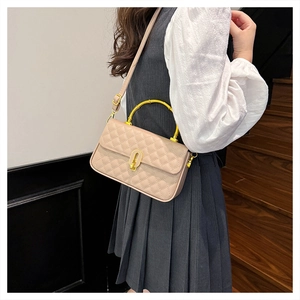 Detail of beige quilted handbag with a golden bamboo handle and rotating metal lock
