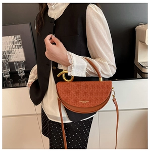 Close-up of brown half-moon bag featuring woven leather texture and gold metal handle