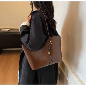 Detail of dark brown tote bag featuring golden rings and black-white braided cord