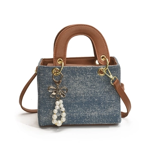 Blue glitter denim handbag with brown leather handles and pearl bow charm detail