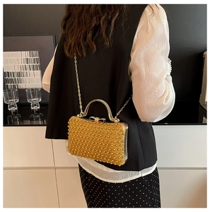 Detail of gold pearl evening bag with rhinestone bow clasp and crossbody chain strap