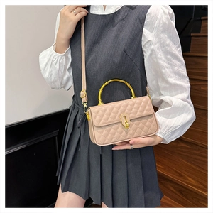 Detail of beige quilted leather box bag featuring a golden bamboo-shaped top handle