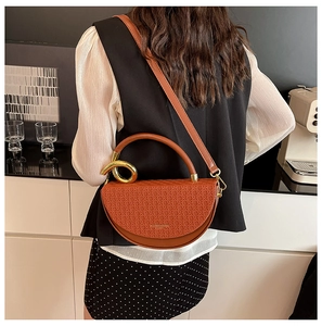 Detail of brown half-moon bag featuring woven texture and gold circular metal handle