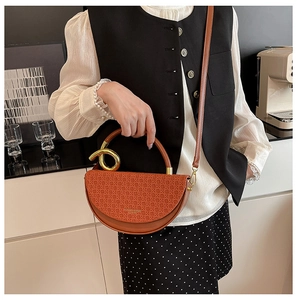 Detail of red-brown crescent handbag with woven flap and gold metal circular handle