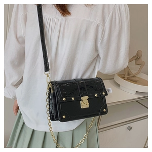 Detail of black faux crocodile skin bag with golden stud rivets and metal chain strap