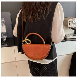 Detail view of orange woven texture handbag with golden metal ring and shoulder strap